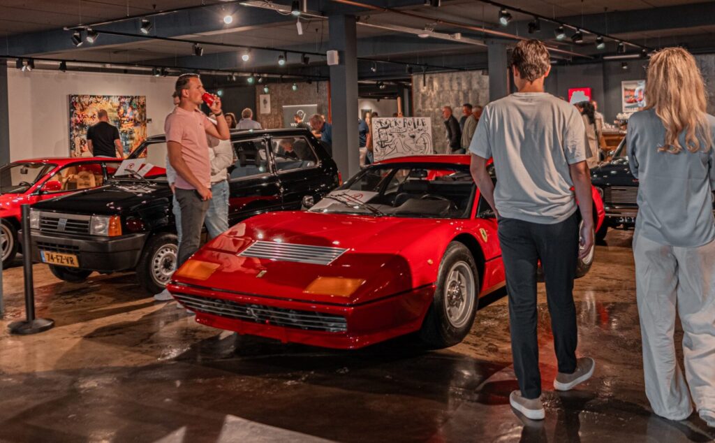 Rode Ferrari 512BB met mensen eromheen in showroom HooG Selections